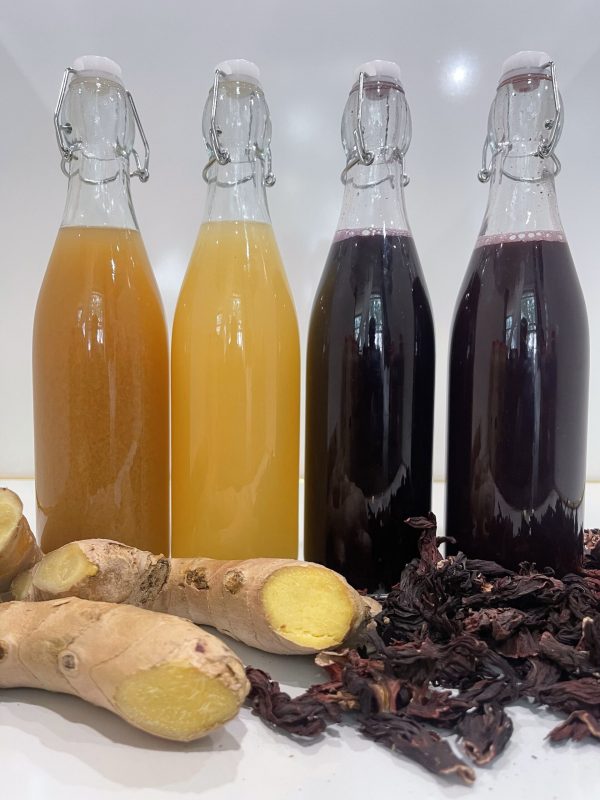 Bottles of MOKAADIA ginger and hibiscus drinks in vibrant packaging, representing Afro-Caribbean and West African-inspired flavors.